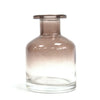 A sleek apothecary style reed diffuser bottle in charcoal glass with a gold finish rim and clear base for bamboo reeds