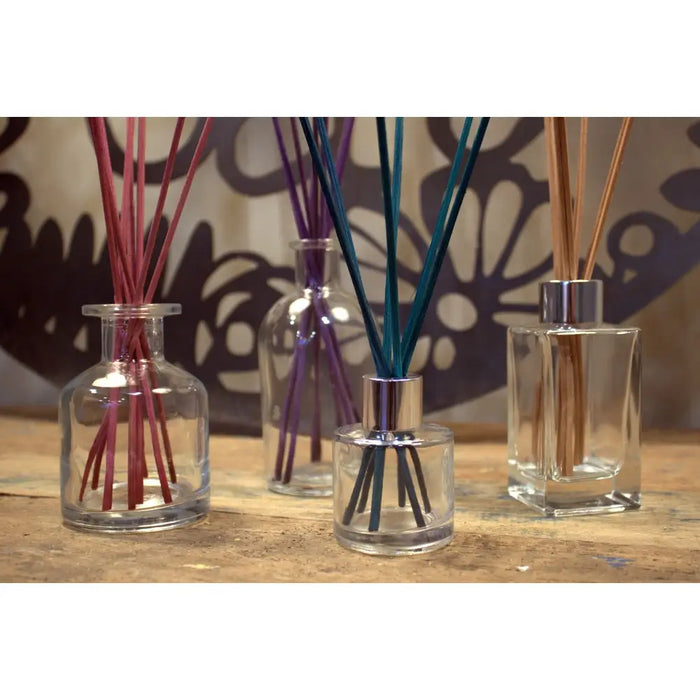 Clear glass apothecary style reed diffuser bottles with metallic finish bottle stopper and colorful bamboo reeds