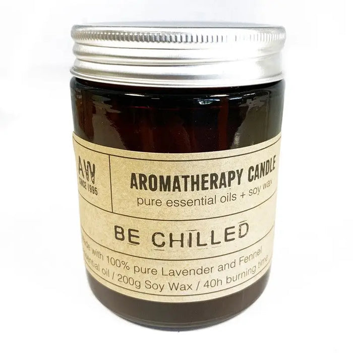 A dark amber glass jar soy wax aromatherapy candle labeled be chilled with lavender and fennel scent and silver lid