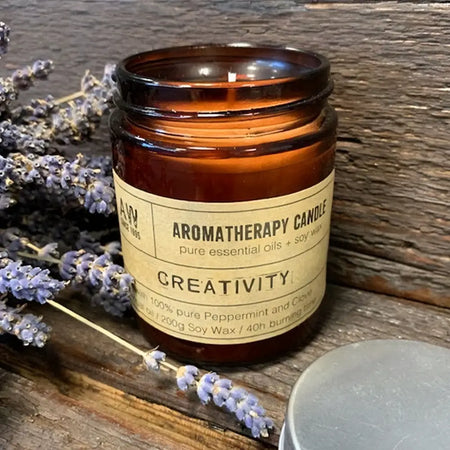 An amber glass jar soy wax aromatherapy candle labeled creativity with pure essential oils
