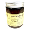 A dark amber glass jar with a silver lid and pale yellow label holds a lavender scented soy wax aromatherapy candle peace