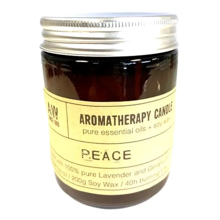 A dark amber glass jar with a silver lid and pale yellow label holds a lavender scented soy wax aromatherapy candle peace