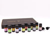 Set of twelve amber glass aromatherapy essential oil bottles with black caps and colorful labels in front of a brown box