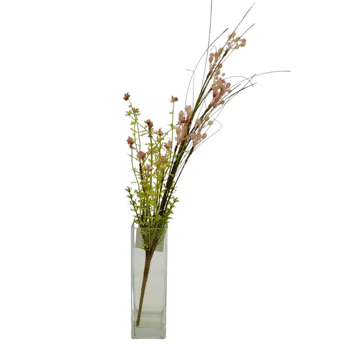 A clear glass vase holding artificial dusky pink berries and green flowering stems in a rectangular shape