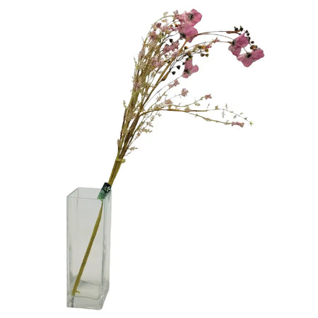 A clear glass vase holding dusky pink helleborus with slender stems and small black berries in dried artificial form