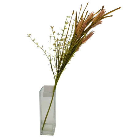 A clear glass vase holding a bouquet of artificial dusky pink wheat with green stems and soft pink brown plumes