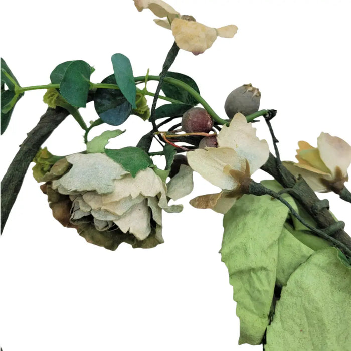 A delicate artificial wild roses branch with cream blossoms green leaves and berries for church pillar candles decor