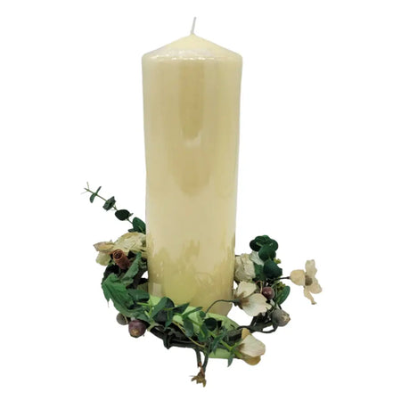 Cream-colored church pillar candle surrounded by dried greenery and white flowers in artificial wild roses table decoration