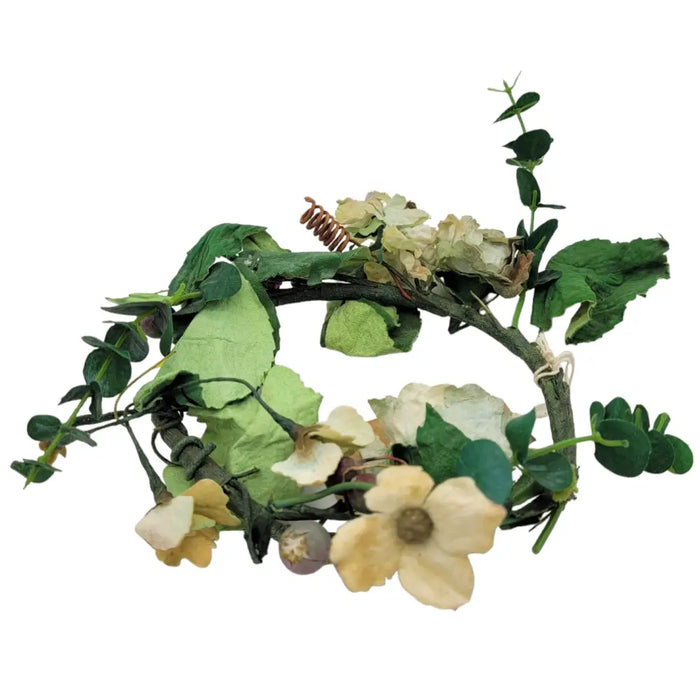 A delicate circular floral crown with artificial green leaves and cream flowers for church pillar candles decor