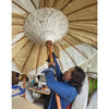 A white intricately woven paper umbrella with a wooden handle shown with an orange canvas bali patio parasol 2m