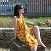 A vibrant yellow wrap dress with a bold black lizard print draped over the shoulders and torso in Bali Sarongs Gecko style