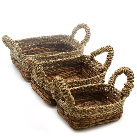 Set of three natural-toned woven banana leaf and seagrass baskets with sturdy twisted handles for storage use