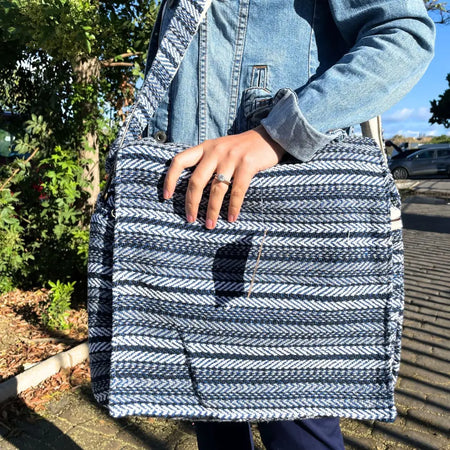 A navy and white herringbone woven banjar laptop bag with a structured rectangular shape and blue stripes