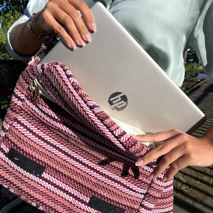 A silver hp laptop inside a pink and white fabric sleeve with a herringbone pattern in the banjar laptop bag design