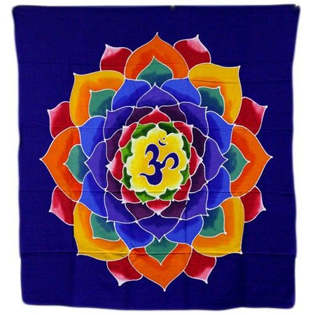 A batik wall hanging with a vibrant multi colored lotus mandala and om symbol on deep blue fabric
