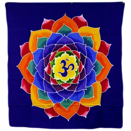 A batik wall hanging with a vibrant multi colored lotus mandala and om symbol on deep blue fabric