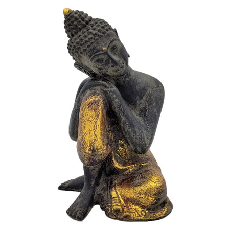 Black and gold resting buddha statue with intricate detailing seated in a meditative pose