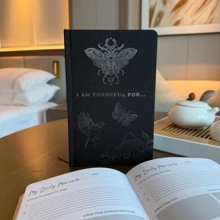 Black gratitude journal with silver embossed butterfly and insect designs and i am thankful for text on the cover