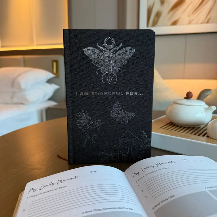 Black gratitude journal with silver embossed butterfly and insect designs and i am thankful for text on the cover