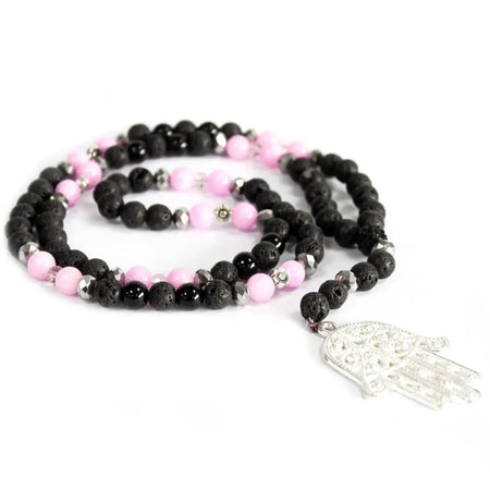 A delicate black lava stone necklace with pink beads and a silver hamsa charm reflecting one’s character