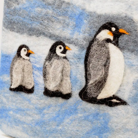 Black yak felt hot water bottles with a penguin family design featuring three black and white chicks on a snowy landscape