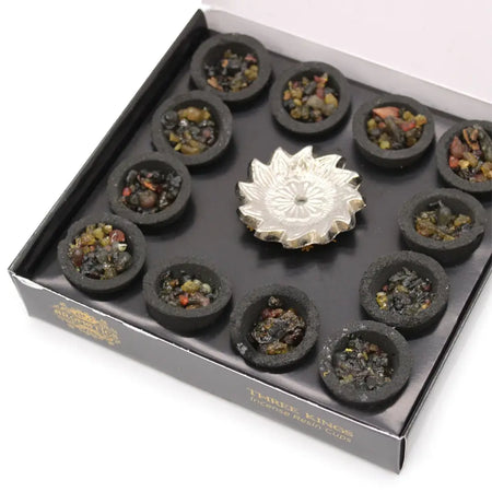 Silver lotus incense burner surrounded by twelve black resin cups filled with colorful incense resin stones