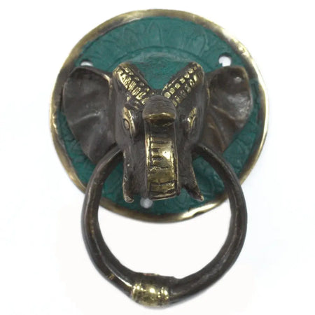 Antique brass door knocker shaped like an elephant head with green patina on a round backplate