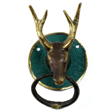 Antique brass stag head door knocker with green patina background and black ring on a door