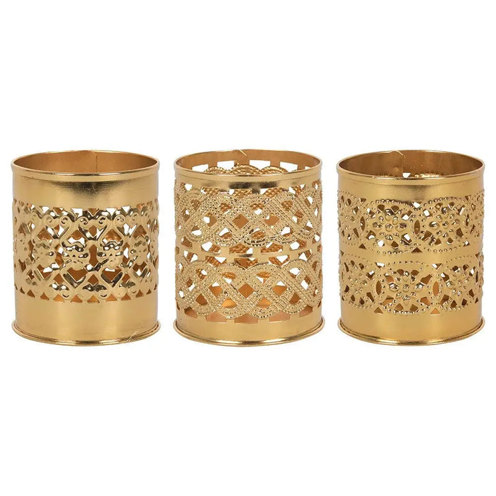 Three brass-finish decorative kasbah tealight holders with intricate cut-out patterns in gold-colored metal