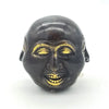 Black ceramic face ornament with gold painted eyes nose and teeth shown with a 10cm brass four face buddha