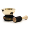 Golden brass singing bowl with black velvet cushion with gold red trim and wooden mallet wrapped in black felt