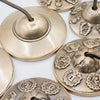 Brass tibetan tingsha bells with intricate engraved lucky symbols and central holes for hanging