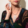 Silver bravery leaf earrings with textured glittery finish on black cord showing leaf-shaped pendant design