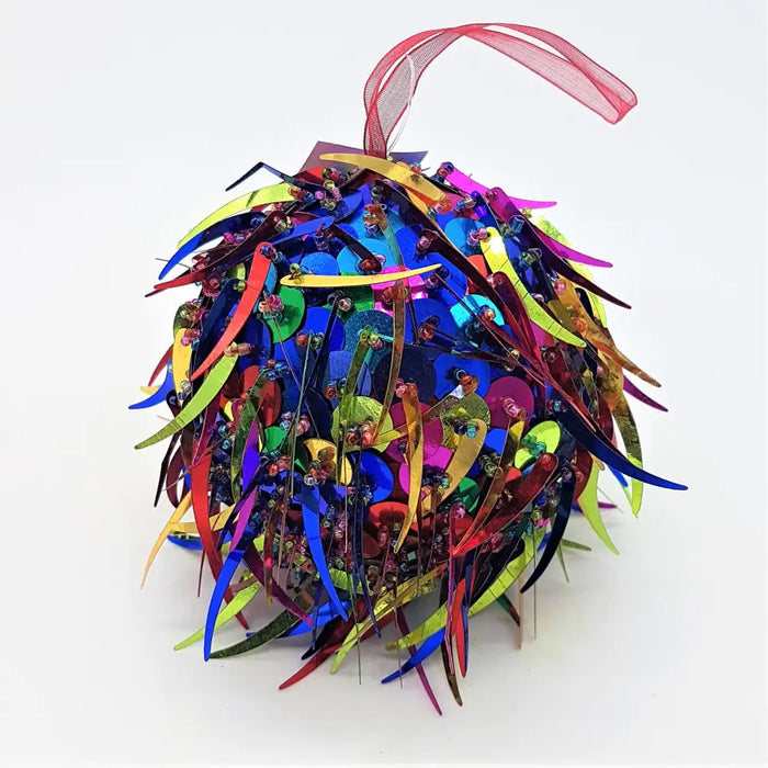 A bright multi-coloured sequinned bauble with spiked sequins and a small diameter hanging by a red ribbon loop