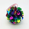 A small diameter bright multi-coloured bauble with spiked sequins and a sheer pink ribbon loop