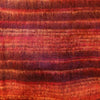 A textured hand-knitted scarf with horizontal stripes in red orange and burgundy shown with brushed cashmelon ali baba trousers