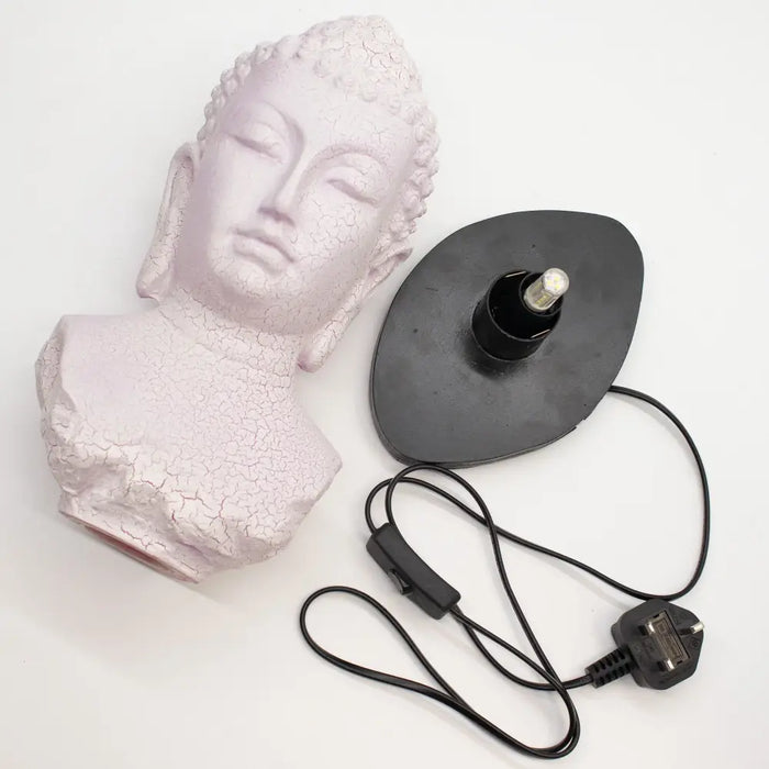 A pale pink buddha glow lamp bust with cherry crackle cracked finish on a black base and cord