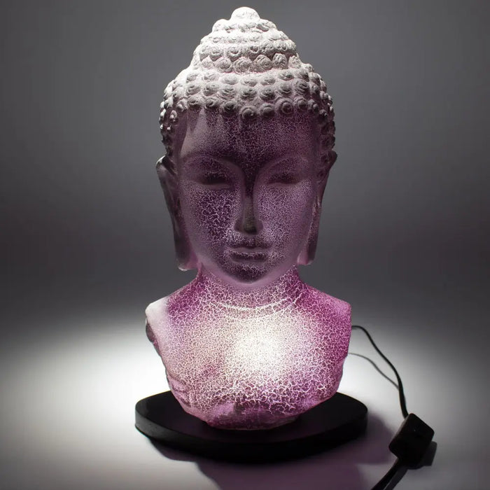 A glowing purple crackled glass buddha head lamp with lavender crackle and a black base bust design