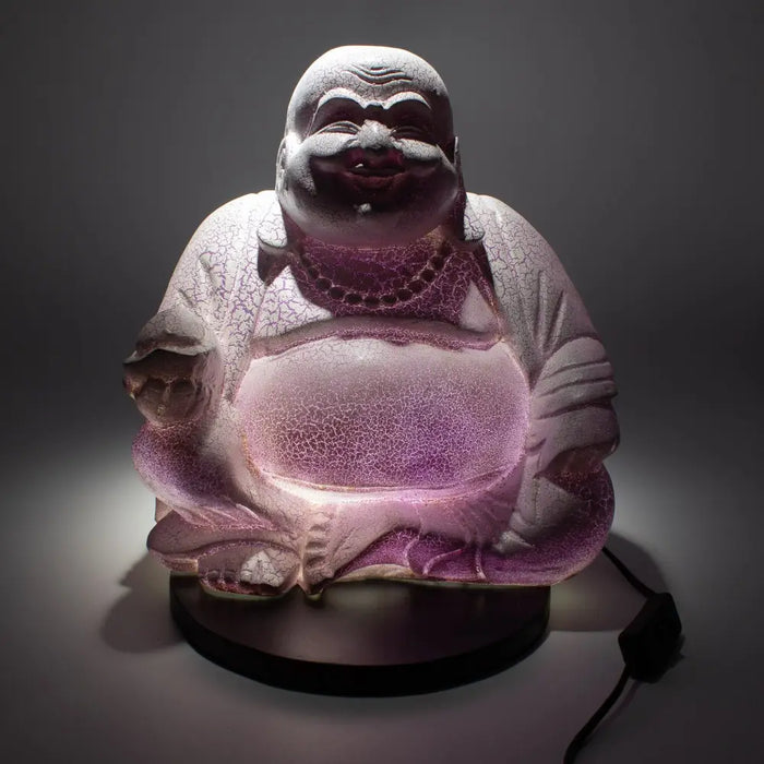 A glowing lavender crackle glass laughing buddha lamp with a smiling face seated and lit from within