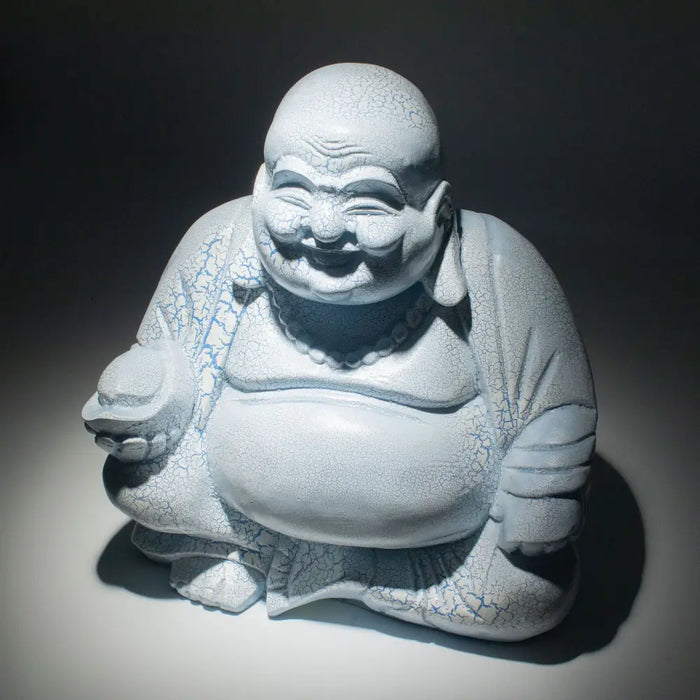 A white ceramic laughing buddha statue with sky blue crackle glaze seated in a meditative pose