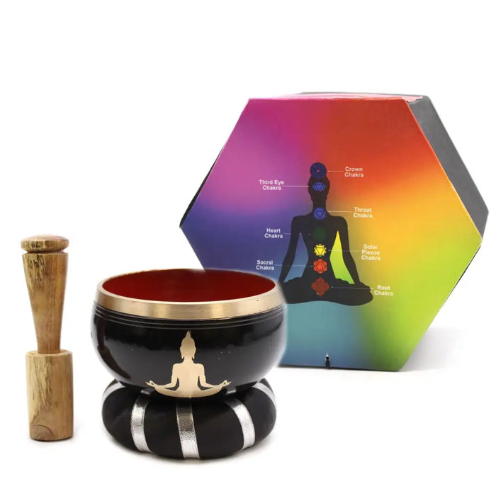 Black tibetan singing bowl set with gold rim and meditating figure on a black and silver striped cushion