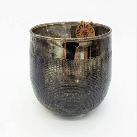 A burnished smoked glass votive candle holder with an etched bronze metallic finish and embossed grid texture