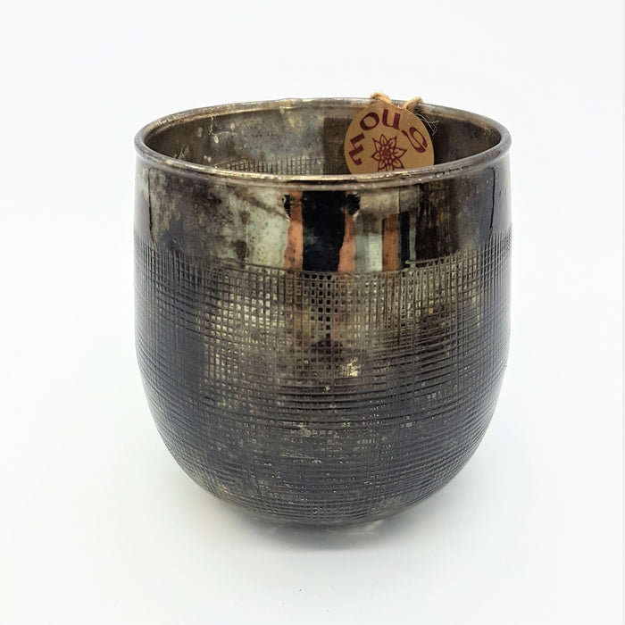 A burnished smoked glass votive candle holder with an etched bronze metallic finish and embossed grid texture
