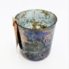 A rustic burnished smoked glass votive with iridescent blues and purples in a mottled oil on water pattern