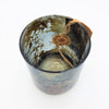 Burnished smoked glass votive candle holder with a dark textured finish and a small brown tag tied to the rim