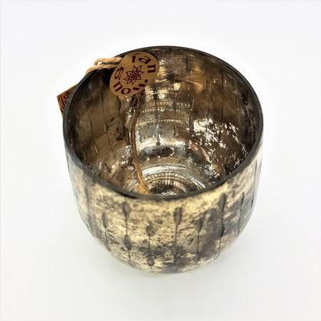 A burnished smoked glass votive with textured gold finish and distressed metallic candle holder with vertical ridges