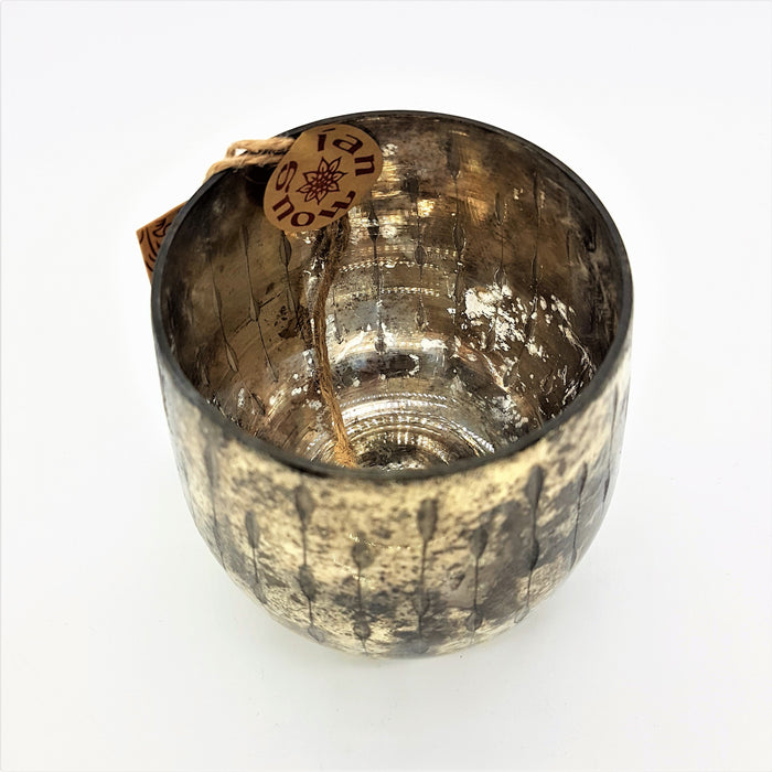 A burnished smoked glass votive with textured gold finish and distressed metallic candle holder with vertical ridges