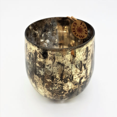 A burnished smoked glass votive candle holder with a textured gold mottled mercury glass finish