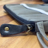 Canvas tablet pouch in olive with gray canvas body black leather zipper pull and white stitching detail