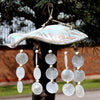 A rustic blue-wash wooden fish wind chime with capiz shells and white beads hanging from five strings